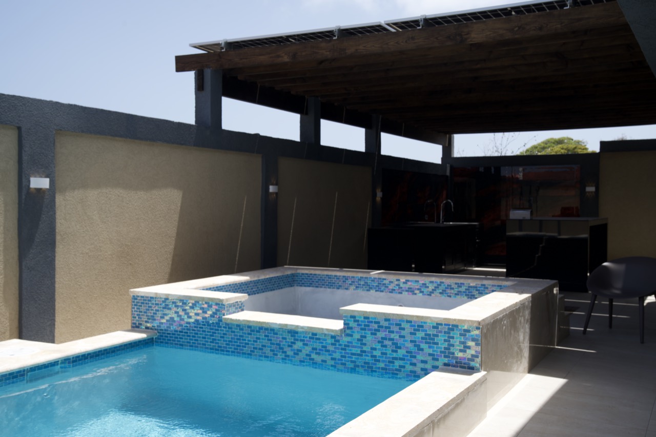 The pool and sun deck at Casabella Suites in San Nicolas, with the single-storey block of suites behind.
