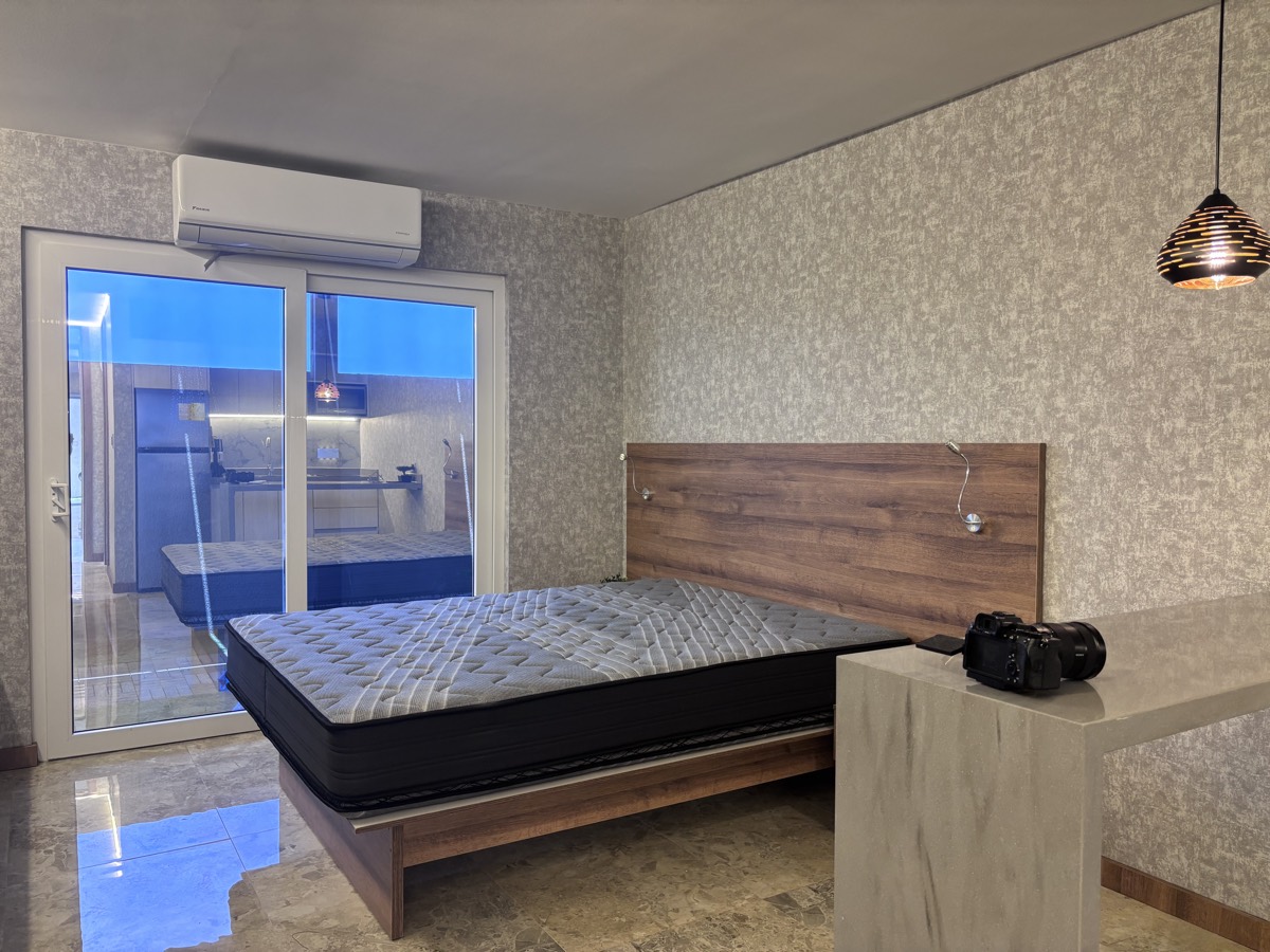 A bedroom in a Casabella suite, with a timber headboard wall and a window to the backyard.