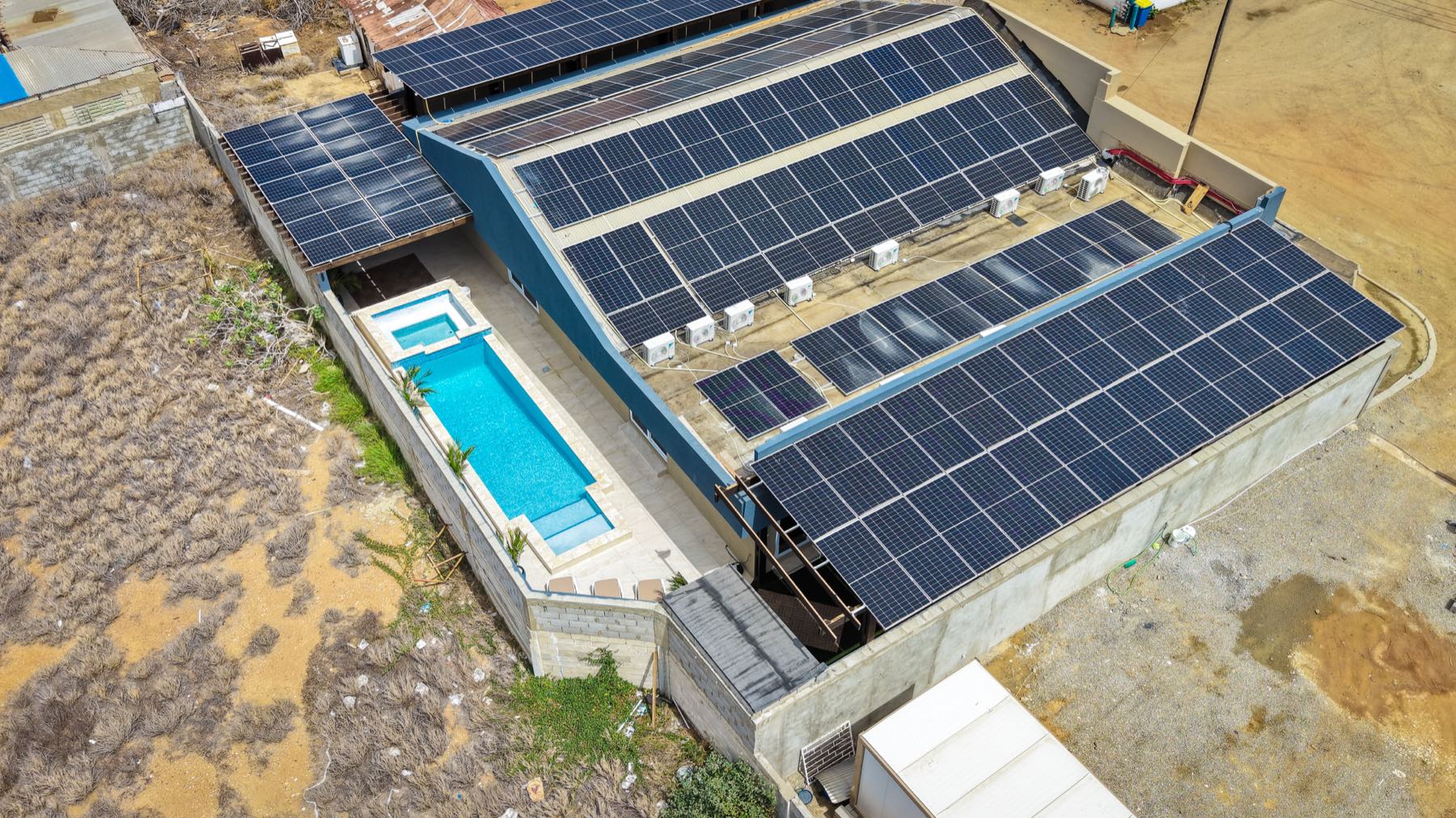 Casabella Suites from the air — the roof covered end to end in solar panels, with the pool alongside the building.