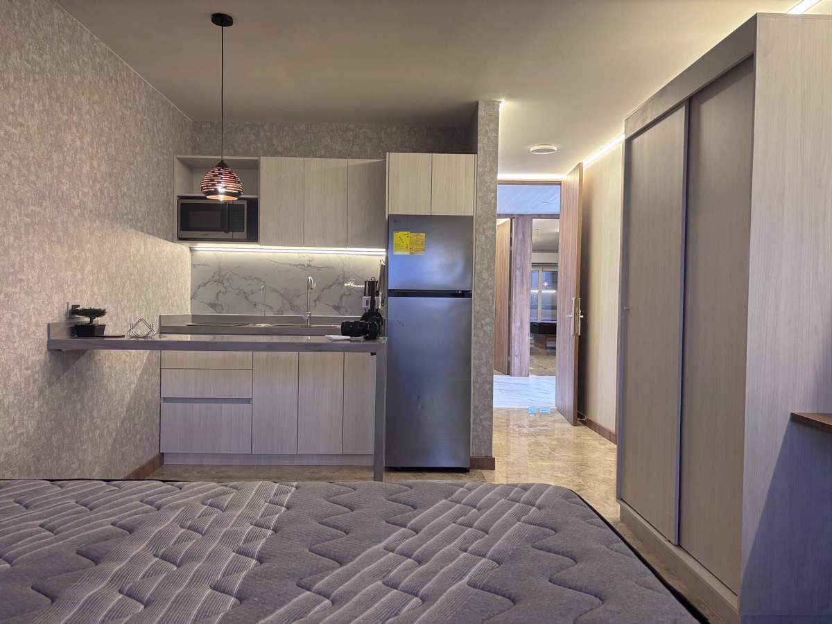 The kitchen in a Casabella suite, with full-height units, a fridge and a worktop under strip lighting.