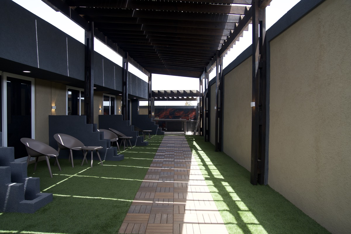 The covered walkway down the middle of Casabella Suites, with suite doors and turf either side.